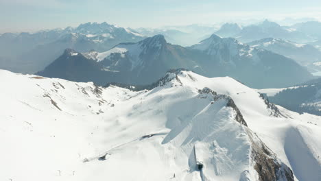 Aerial-tilt-up-of-beautiful-snow-covered-mountain-summit-and-revealing-a-stunning-view-of-the-Swiss-Alps