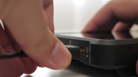 Man-hand-plug-and-unplug-HDMI-cable-into-external-monitor-closeup