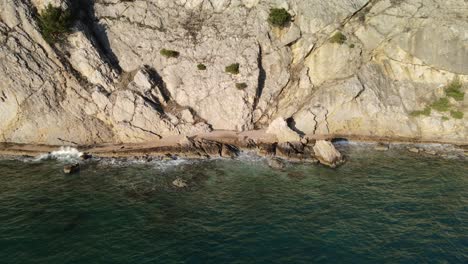 Aerial-dolly-shot-right-with-drone-on-the-coast-of-Beska-in-Croatia-following-a-woman-walking-next-to-adriatic-sea