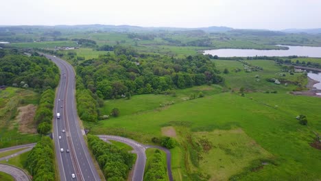 Aerial-forward-over-highway-crossing-green-Scottish-countryside