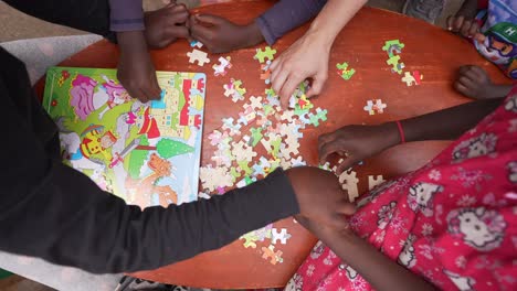 Niños-Africanos-Haciendo-Un-Rompecabezas-Con-Un-Voluntario-Blanco-En-El-Orfanato