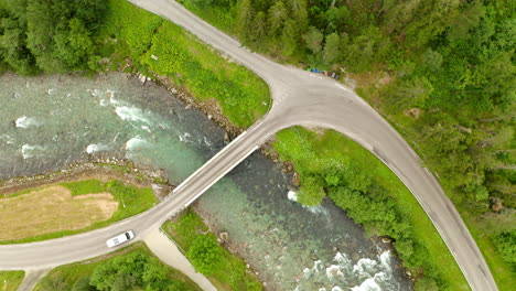 Vista-Aérea-De-Un-Vehículo-Que-Circula-Por-Un-Pequeño-Puente-Sobre-Un-Curso-De-Agua-En-Geiranger,-More-Og-Romsdal,-Noruega
