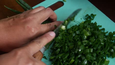 Top-view-of-Women's-hands-cut-green-onions-with-a-knife-on-a-board