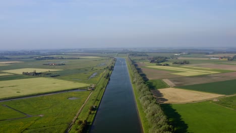 Aerial-shot-high-over-the-Canal-through-Walcheren-and-surrounding-agricultural-land-in-Zeeland,-the-Netherlands,-on-a-sunny-summer-day