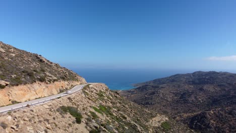 Car-driving-on-the-road-to-Magganari-beach,-Ios-island,-Greece