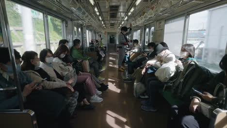 Pasajeros-Con-Máscaras-Dentro-De-Un-Tren-En-Movimiento-En-Sendai,-Japón-Durante-Una-Pandemia