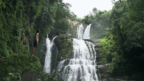 Man-gazes-at-Nauyaca-waterfalls-Costa-Rica-rain-forest,-slow-motion