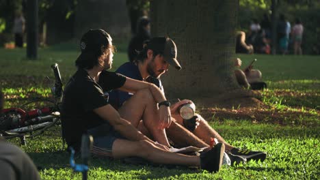 Two-young-adults-sit-in-conversation,-resting-at-the-park
