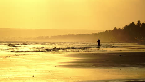 Silhouetted-man-fishing-on-a-tropical-beach-in-Vietnam-at-sunset