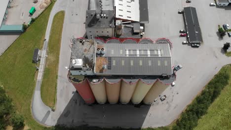 Top-down-aerial-sliding-view-of-Lantmännen-Lantbruk-industrial-crops-storage-warehouse-and-large-agricultural-grains-silos-located-in-rural-Brålanda-town-Vänersborg-Sweden