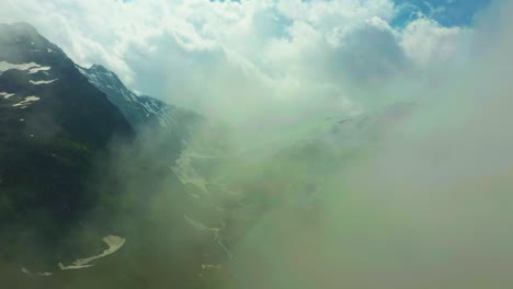 Drone-fly-into-clouds-in-scenic-snowy-mountains-in-Alps,-Switzerland
