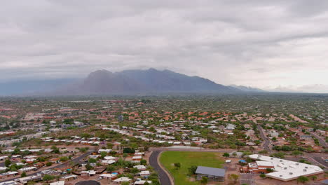 Revealing-drone-shot-of-Tucson-Arizona-with-slight-cloud-cover-and-mountains-in-the-distance