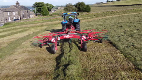 Aerial-flyover-of-a-tractor-collecting-hay-in-a-row