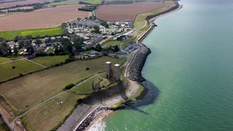 High-altitude-drone-video-showing-the-Reculver-Towers-next-to-the-sea-in-the-summer-sunshine