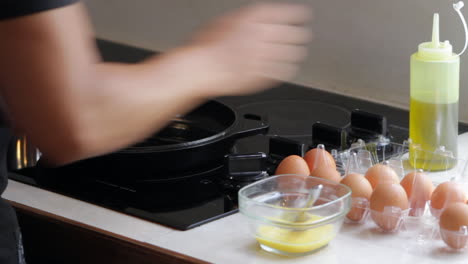 Man-puts-oil-in-pan-and-cooks-scrambled-eggs
