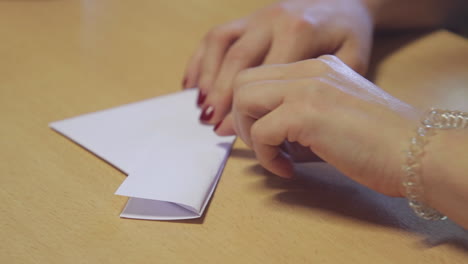 Close-up-of-a-women's-hands-folding-an-origami-boat