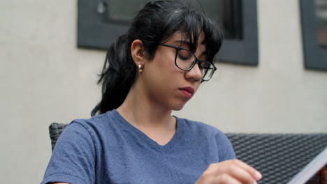 A-young-Latina-woman-wearing-glasses-studies-a-textbook