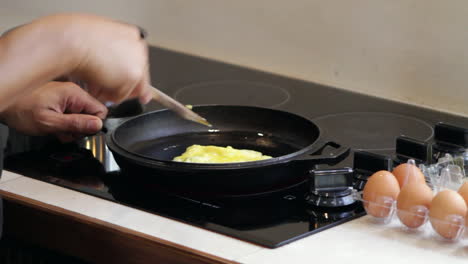 Man-fries-and-flips-egg-omelet-in-cast-iron-skillet