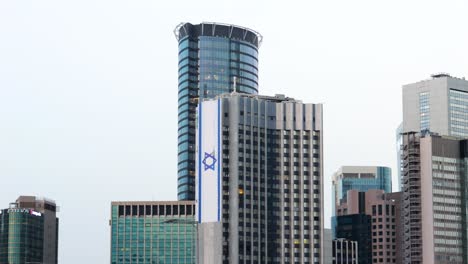 Gran-Bandera-Israelí-En-Rascacielos-Altos-En-El-Centro-De-Tel-Aviv