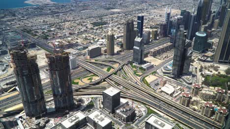 Blick-Von-Der-Spitze-Des-Burj-Khalifa-Auf-Gebäude,-Die-Gebaut-Werden,-Und-Auf-Stark-Befahrene-Straßen