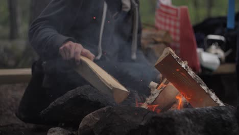 Man-putting-more-wood-in-forest-fire-slow-motion-fire