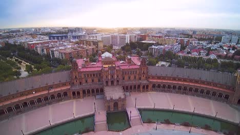 Drone-shot-of-Plaza-de-España-in-Seville-flying-towards-the-rising-sun,-sunrise,-summer,-sun