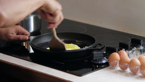 Man-cooks-eggs-in-cast-iron-skillet