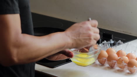 Beating-eggs-in-a-glass-bowl-on-kitchen-counter-near-stove-top-in-kitchen