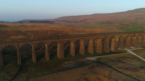Aerial-Drone-Shot-Rotating-Around-Ribblehead-Viaduct-Train-Bridge-at-Stunning-Sunrise-in-Summer-in-Yorkshire-Dales-England-UK-with-3-Peaks-Whernside-Mountain-in-Background