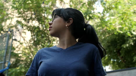 A-young-Latina-woman-wearing-glasses-looks-up-to-the-sky-and-trees-on-a-sunny-day