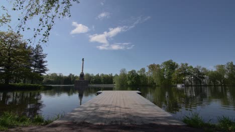 Royal-lake-in-Pushkin-with-an-obelisk-in-water-and-pierce,-trees-on-an-island-and-sun-flares
