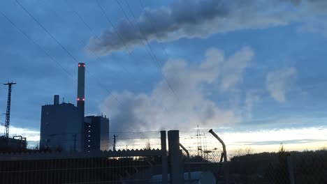 Power-plant-in-industrial-area-in-front-of-blue-dusk-sky-producing-a-huge-vapor-cloud