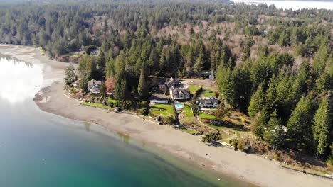 Drone-flying-toward-luxury-home-on-beach-coast