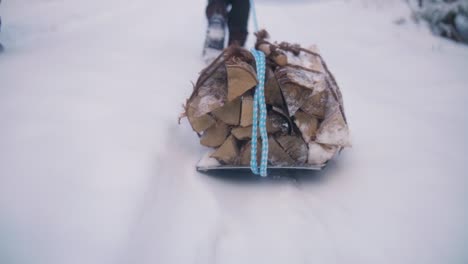 Holz-Auf-Schlitten-Auf-Einem-Winterweg,-Der-Von-Einem-Touristen-Auf-Schnee-Getragen-Wird