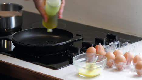 Man-puts-oil-in-pan-to-cook-eggs