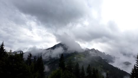 Timelapse,-pan-left-to-right,-showing-the-mountain-Alpsitze-of-german-alps-with-many-clouds-wrapping-around-during-evening-time-after-a-heavy-storm