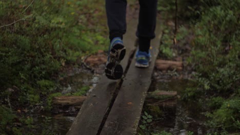 Close-up-on-sport-shoes-with-blue-color-on-a-small-bridge-over-forest-stream-dark-moody-atmosphere-autumn