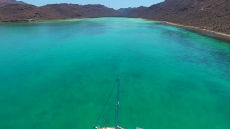 Rising-Aerial-View-of-Girl-on-Sailboat-Anchored-in-Clear-Emerald-Water-Desert-Cove