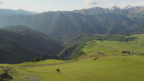 Wide-paning-drone-shot-of-man-riding-a-horse-in-upper-Omalo,-Tusheti-Georgia