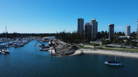 Revealing-drone-view-of-a-government-infrastructure-project-in-a-boating-marina-and-harbor-next-to-a-towering-city-skyline