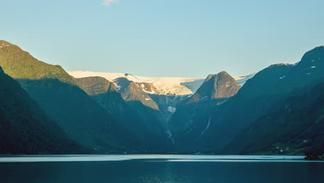 Scenic-View-Of-Briksdalsbreen-Glacier-Behind-Mountain-Ridges-Surrounding-Olden-Lake-In-Norway