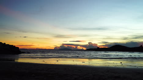 Calm-tides-crashing-on-beach-shore-at-dusk,-colorful-orange,-pink,-blue-sky