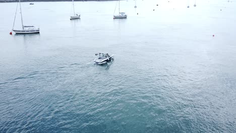 Freizeit-Motorboot-Luftaufnahme,-Die-Zwischen-Yachten-Auf-Dem-Ruhigen-Fluss-Conwy-Harbour-Navigiert