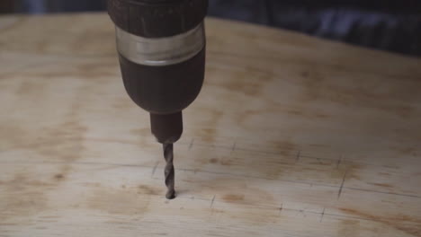 A-person-using-an-electric-drill-to-bore-a-hole-in-a-piece-of-plywood