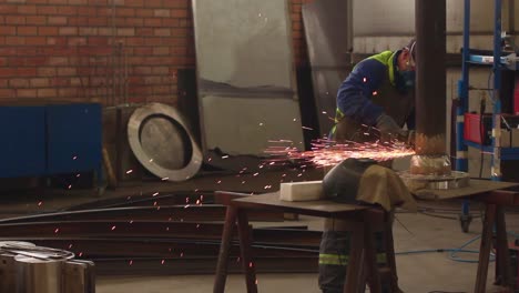 Worker-using-a-grinder-and-cutting-metal-in-a-industrial-space,-with-sparks-effect