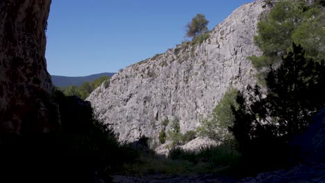 Silhouette-Der-Höhlenmündung-Mit-Büschen-Gegen-Eine-Sonnenbeschienene-Felswand,-Spanien