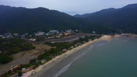 drone-shot-of-a-public-beach-with-mountains-and-forest-around-during-the-day