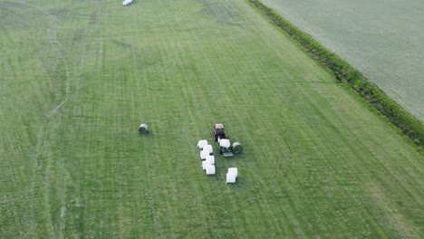 Hay-bale-spinning-on-machine-wrapping-in-white-foil-on-green-countryside-in-Iceland