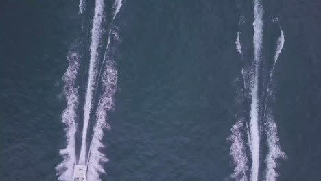 Rising-overhead-aerial-of-powerboats-rushing-fast-on-calm-water