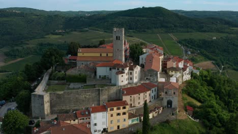 Aerial-shot-circling-around-the-old-walled-town-of-Motovun,-Croatia-on-a-bright-afternoon